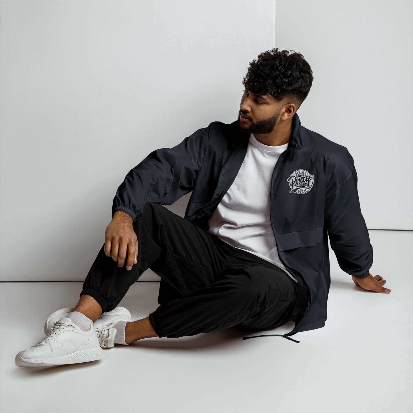 Young man wearing Real Men Pray windbreaker, showcasing Christian clothing in a modern style.