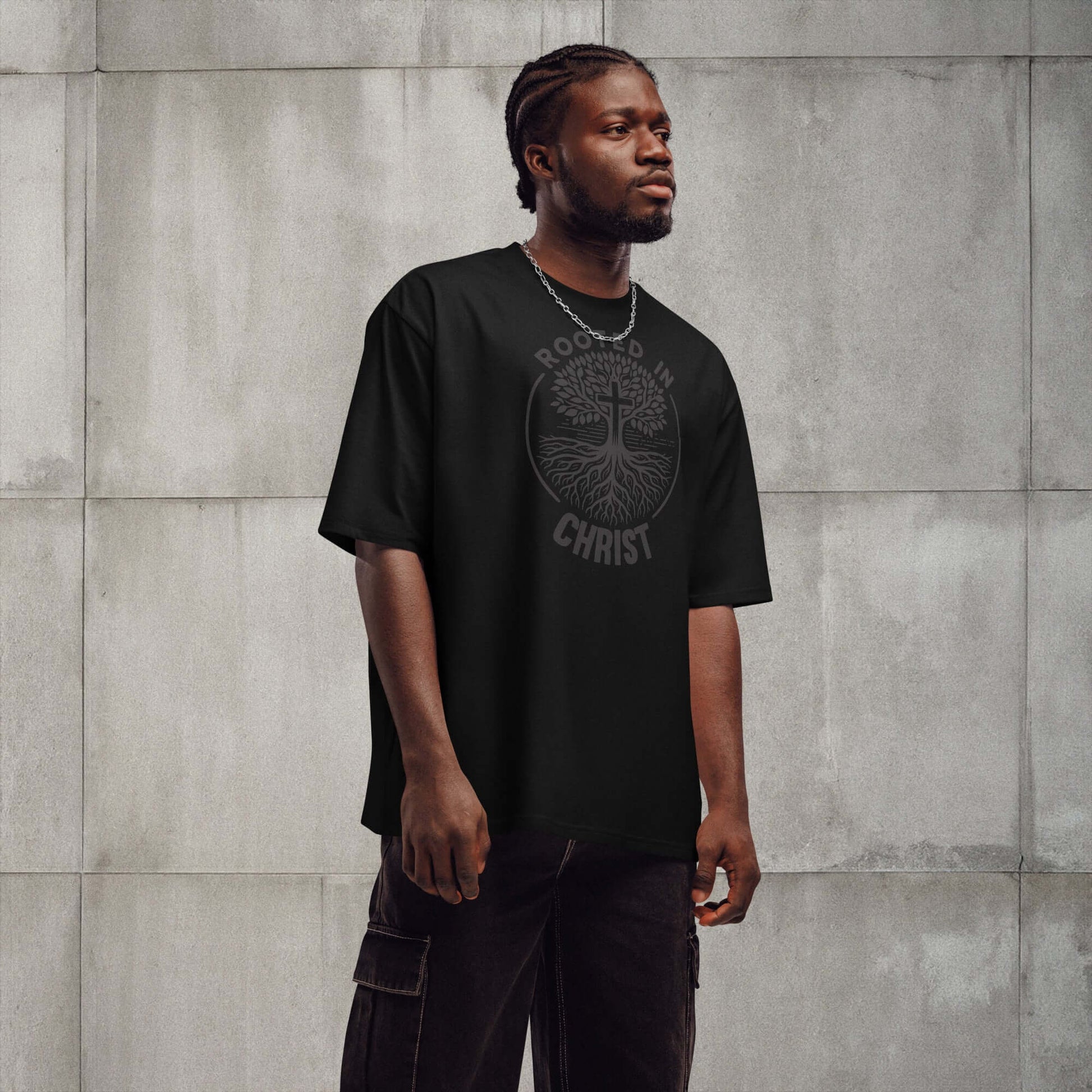 Black oversized "Rooted in Christ" t-shirt worn by a model, showcasing Christian clothing style in the UK.