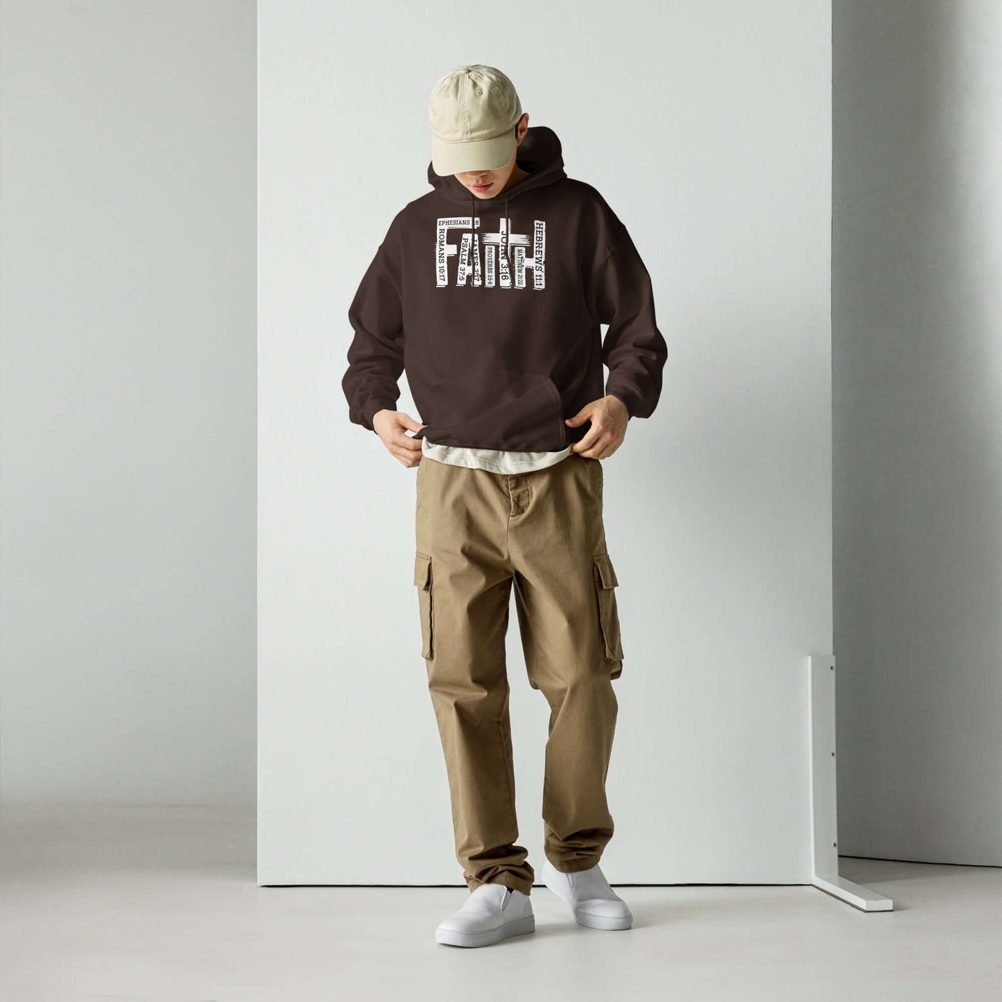 Man wearing a "Faith" Christian hoodie in brown, inspired by Hebrews 11:1, paired with beige cargo pants and white sneakers, representing Christian clothing UK.