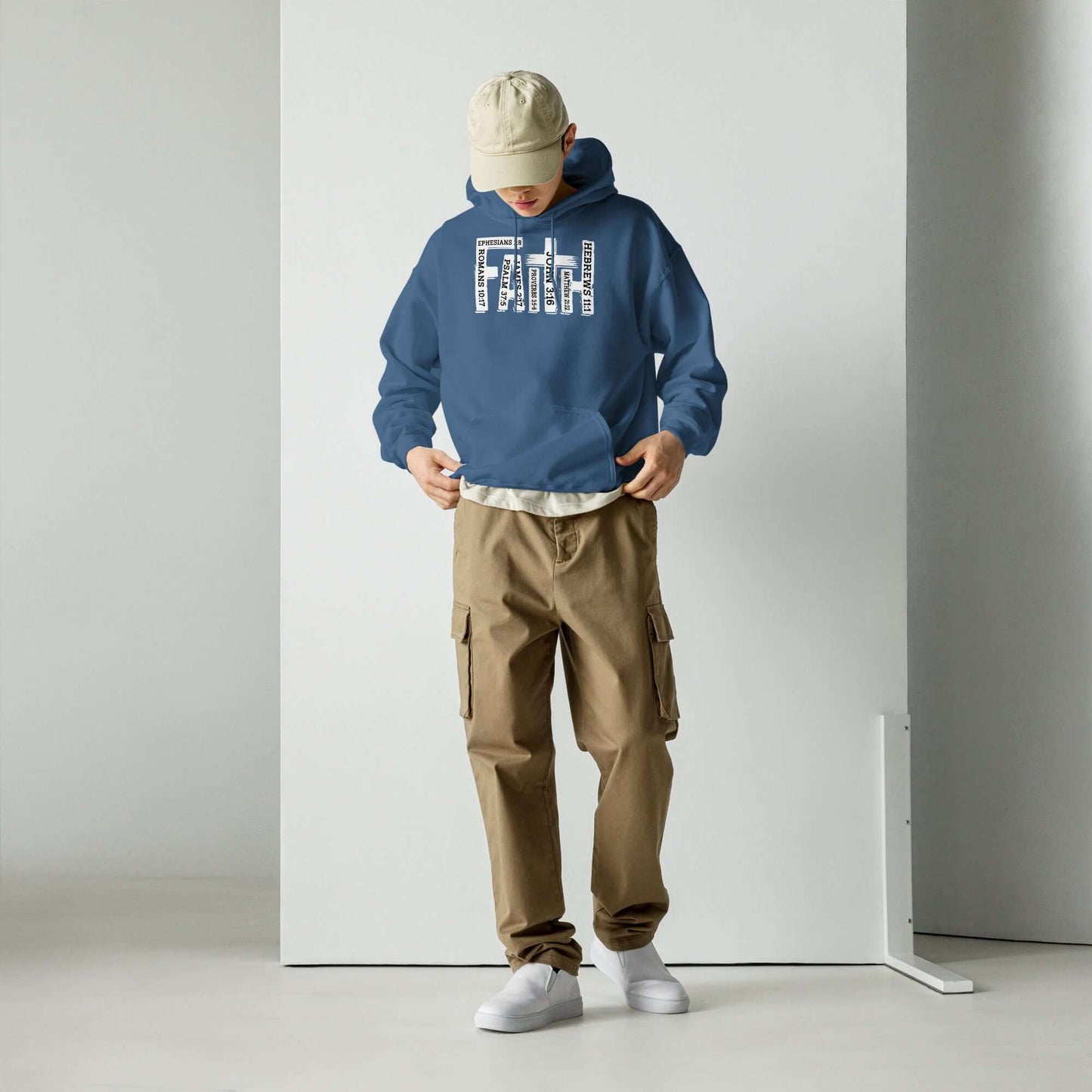 Man wearing "Faith" Christian hoodie inspired by Hebrews 11:1, styled with cargo trousers and white sneakers, showcasing Christian clothing UK.