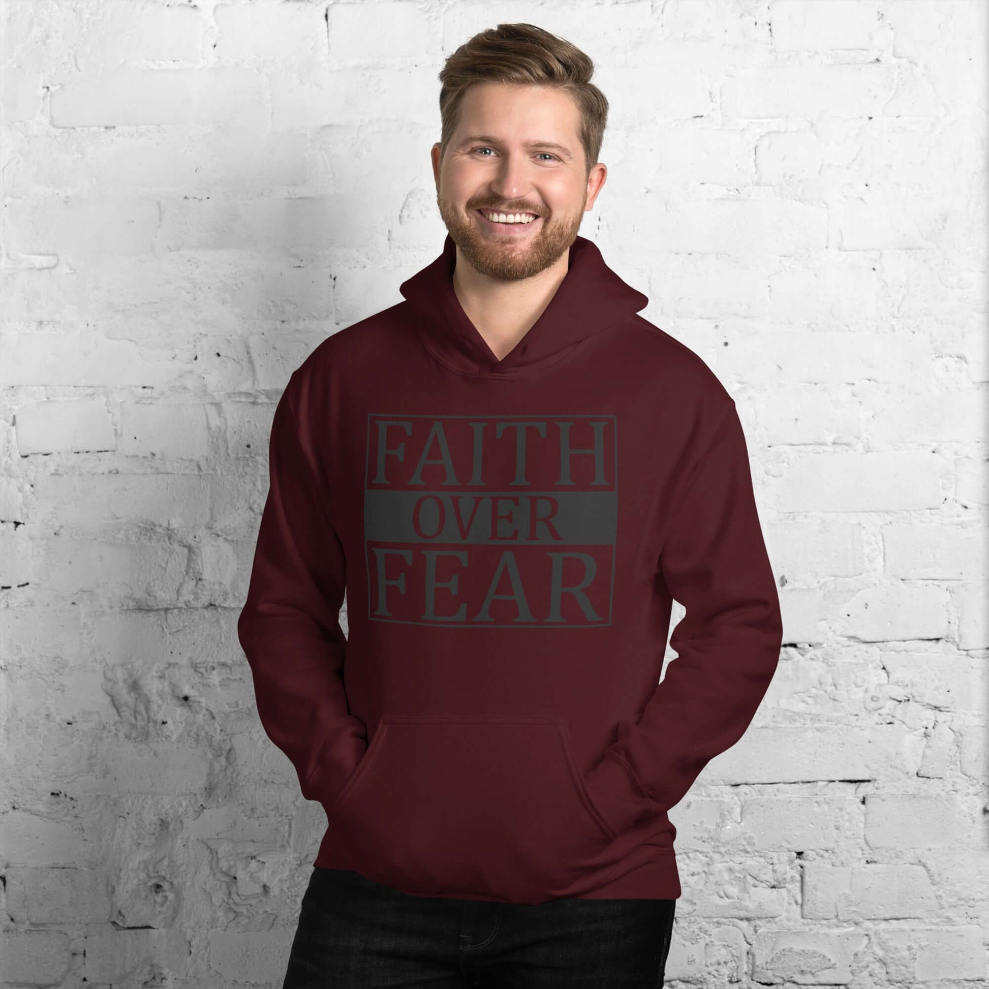 Man wearing a maroon "Faith Over Fear" hoodie, symbolizing Christian courage and comfort in faith. Christian Clothing UK.