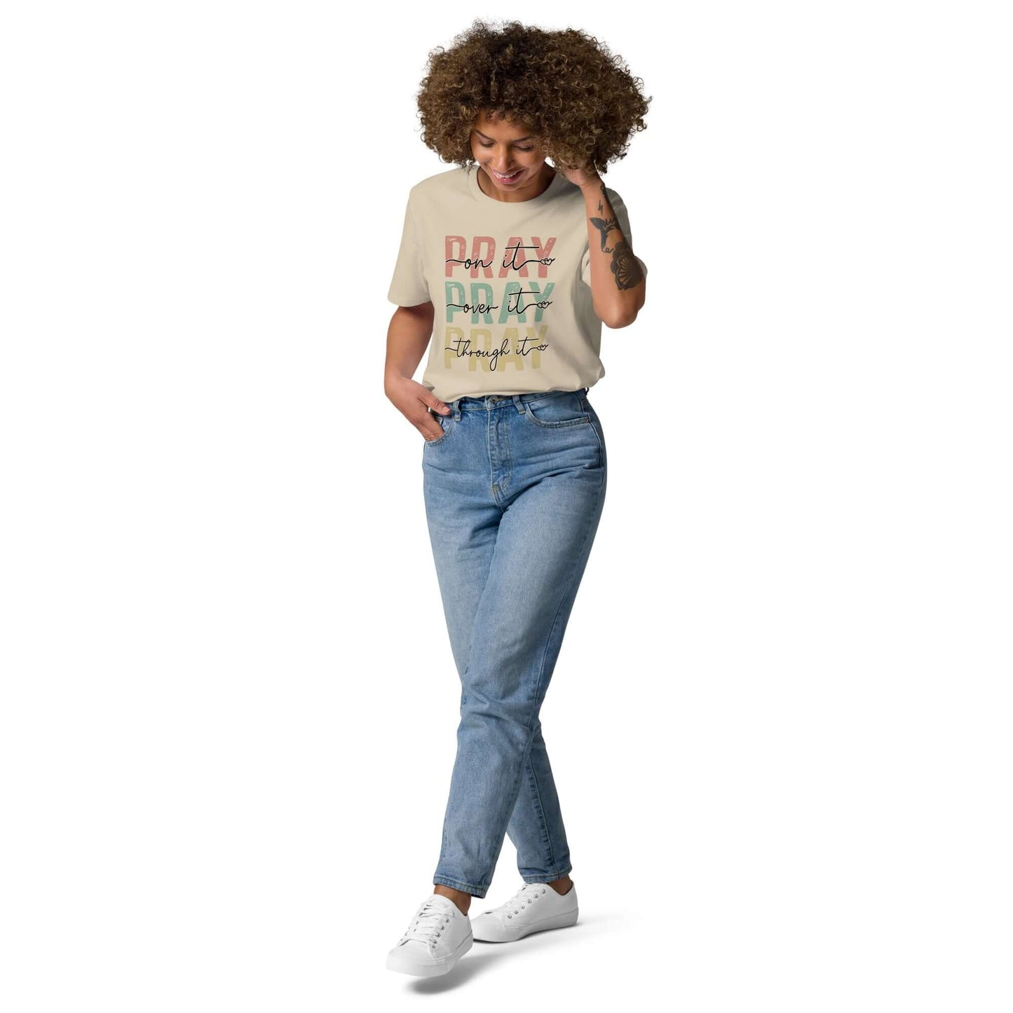 Woman in a "Pray" organic cotton t-shirt, promoting faith and positivity, styled with casual jeans and sneakers.