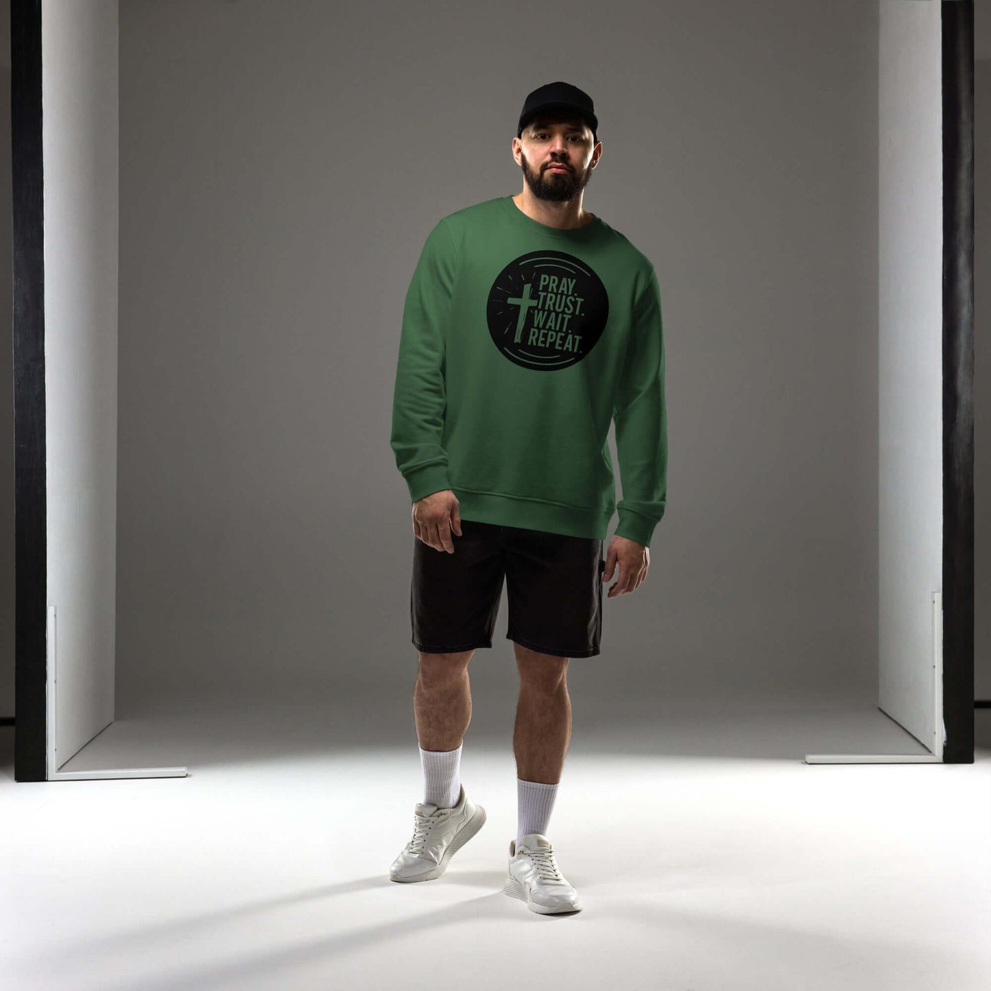 Man wearing green "Pray. Trust. Wait. Repeat." Christian sweatshirt, showcasing inspirational minimalist design and comfort.