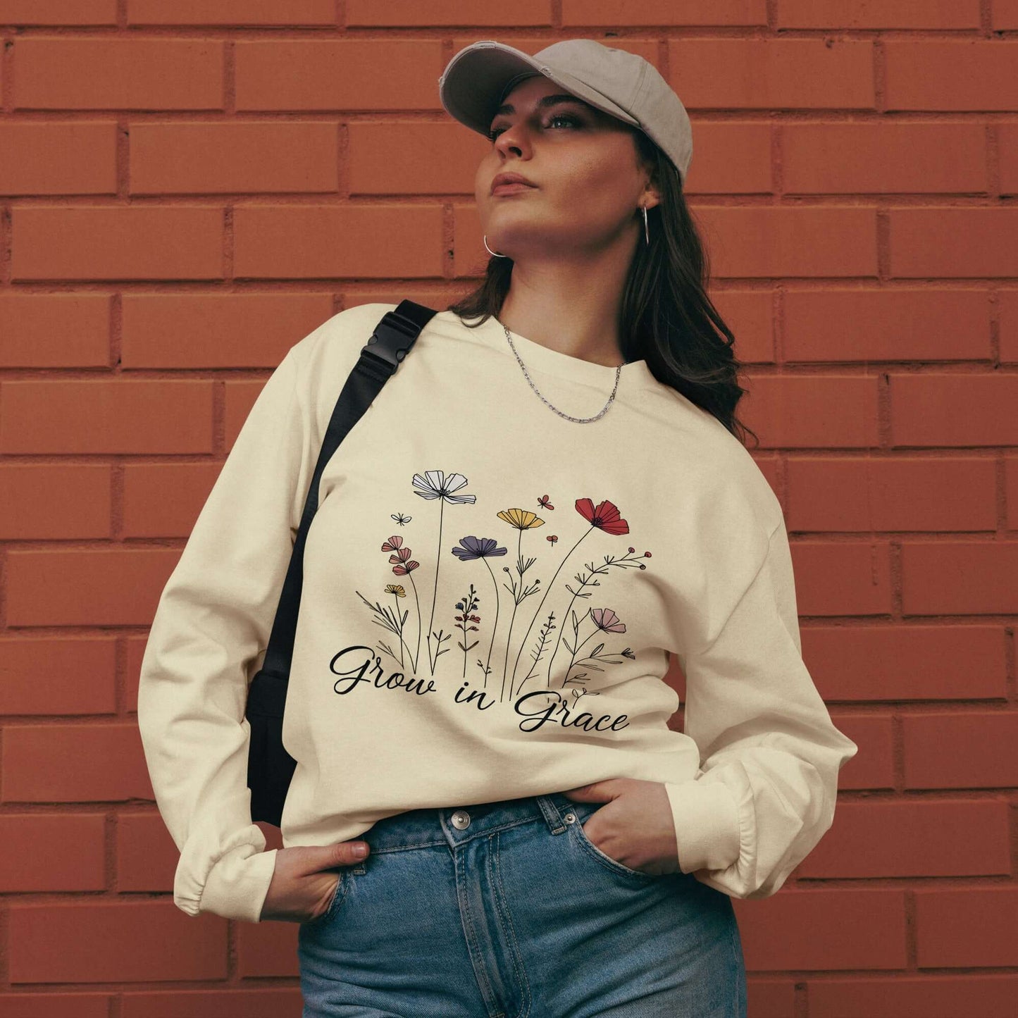 Woman wearing "Grow in Grace" Christian sweatshirt against a brick wall, embodying inspiration and faith.