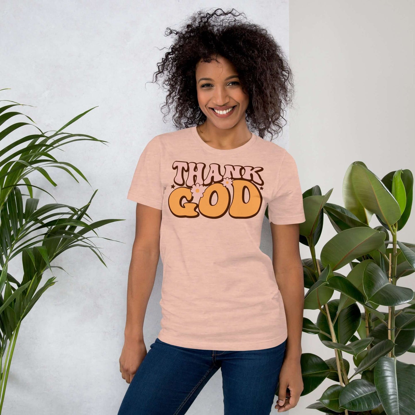 Woman wearing "Thank God" Christian T-shirt, showcasing modern typography, surrounded by greenery.