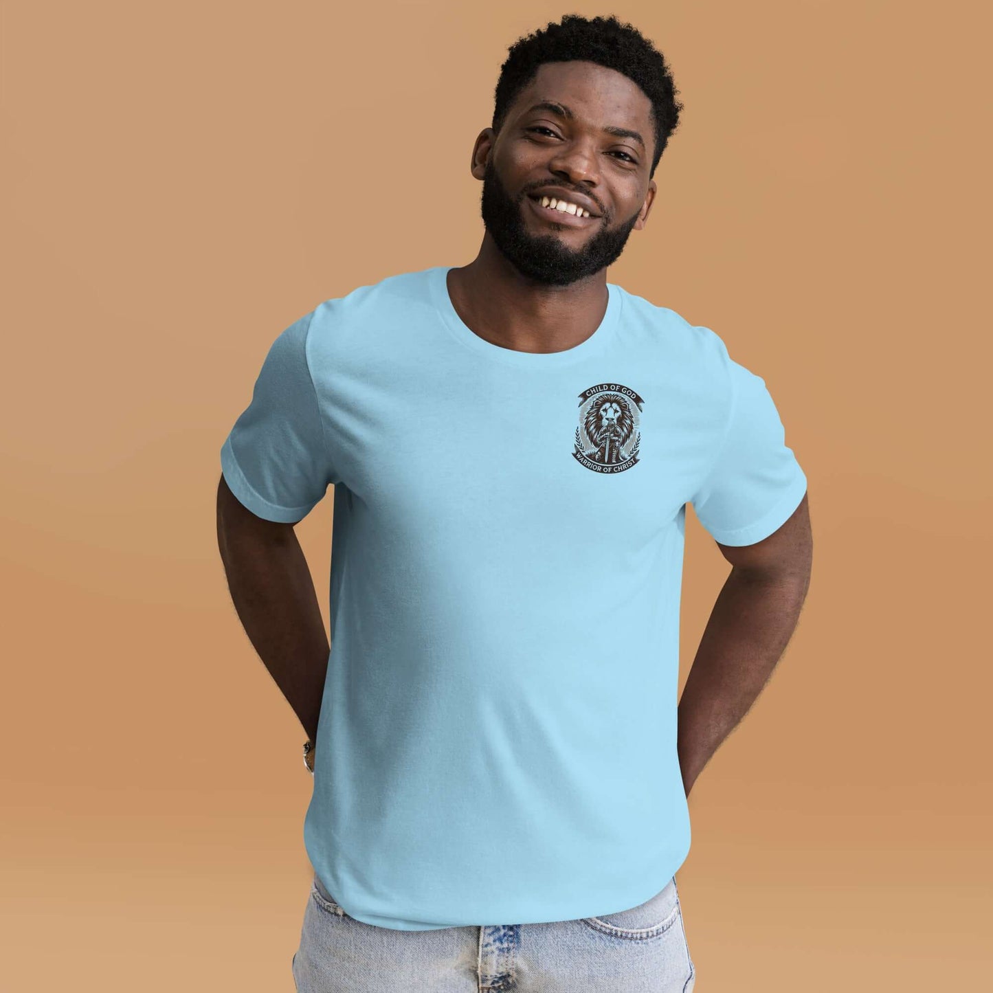 Smiling man wearing a light blue Christian T-shirt with a small emblem on the chest, standing against an orange background