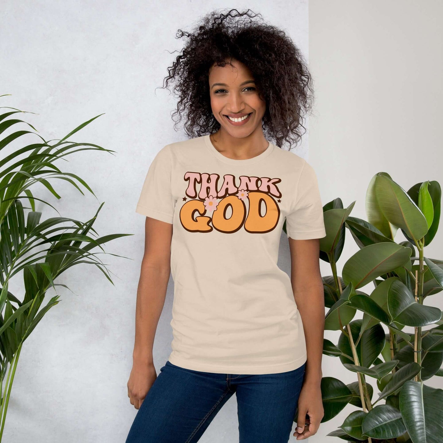 Woman wearing "Thank God" Christian T-shirt surrounded by greenery, promoting faith and gratitude in style.